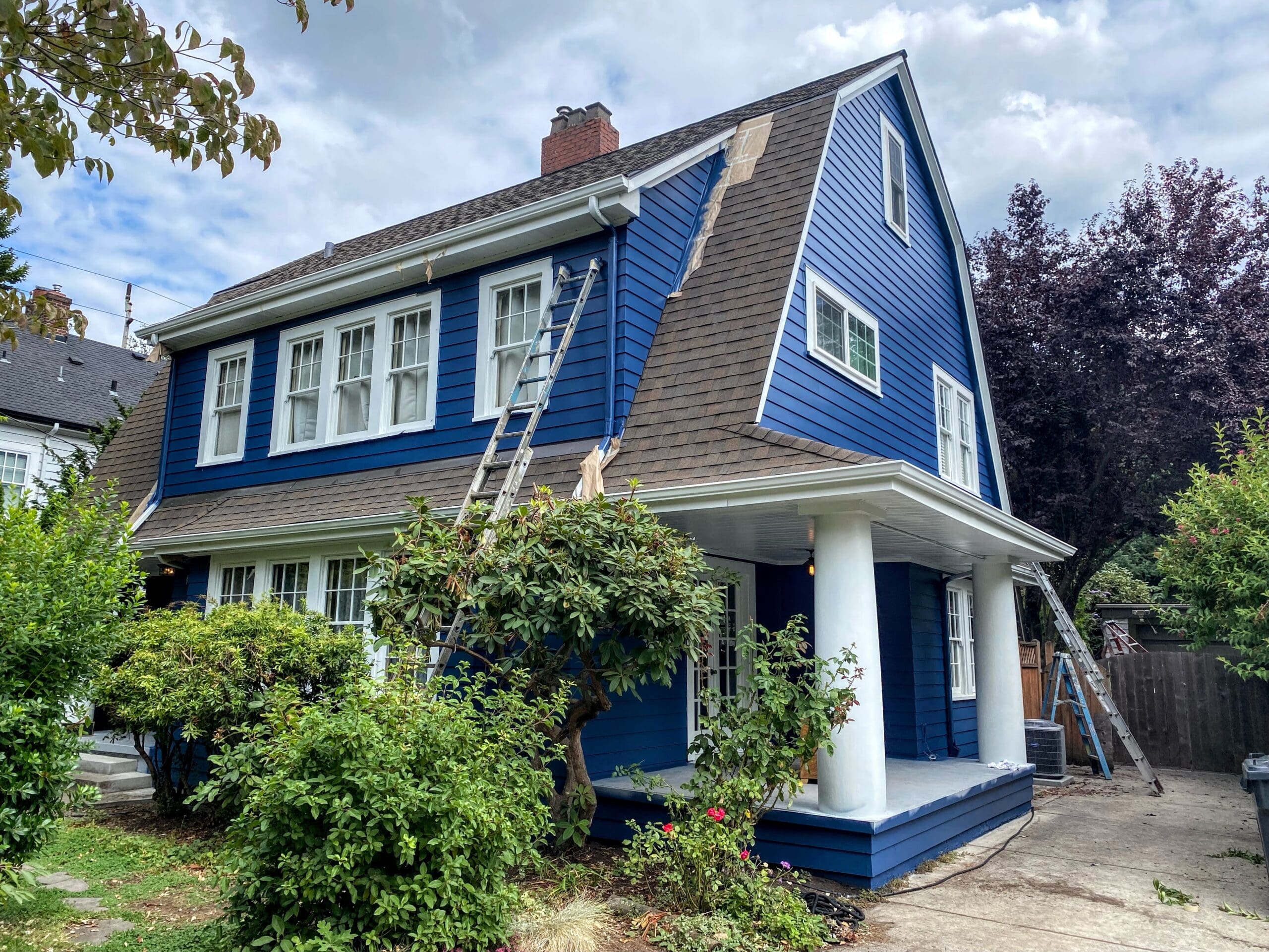 New, blue siding being installed and painted on a traditional farmhouse to illustrate best home upgrades.