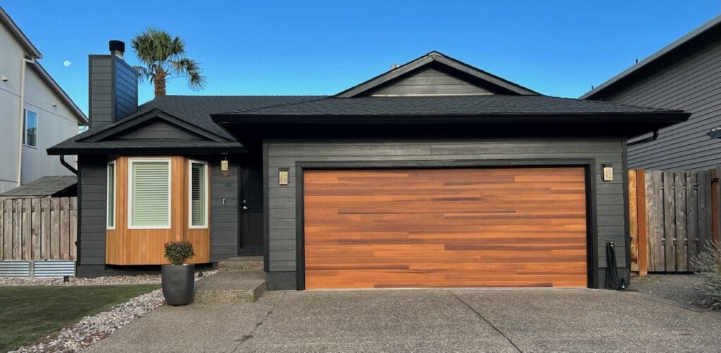 A sleek looking home with new black siding and a cedar garage door to illustrate best exterior home improvements.