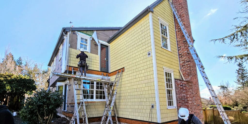 Workers installing new siding on a home to help illustrate the best ROI exterior home improvements.