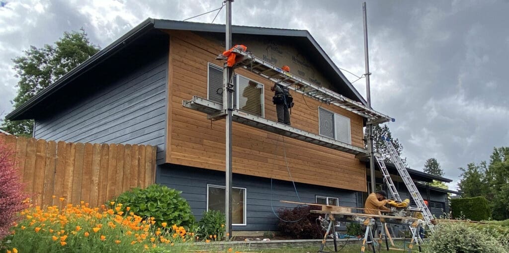Crews on scaffolding installing new siding on a home to help illustrate does new siding increase home value.