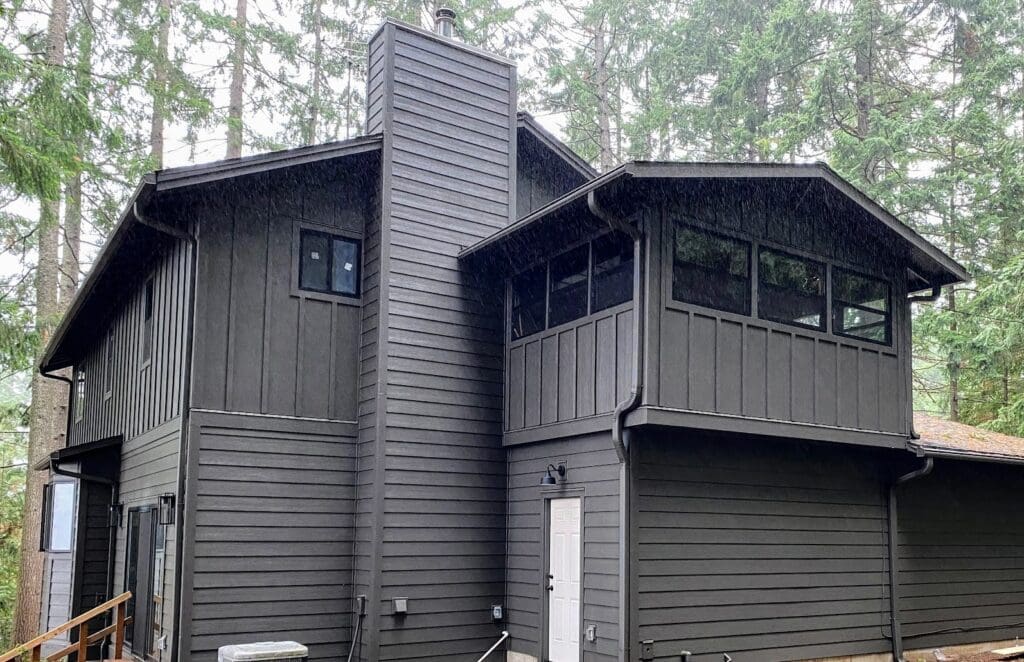 A home with new dark gray siding in the woods to illustrate energy efficient siding.